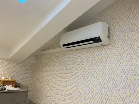 Climatiseur mural installé au-dessus d'une tête de lit